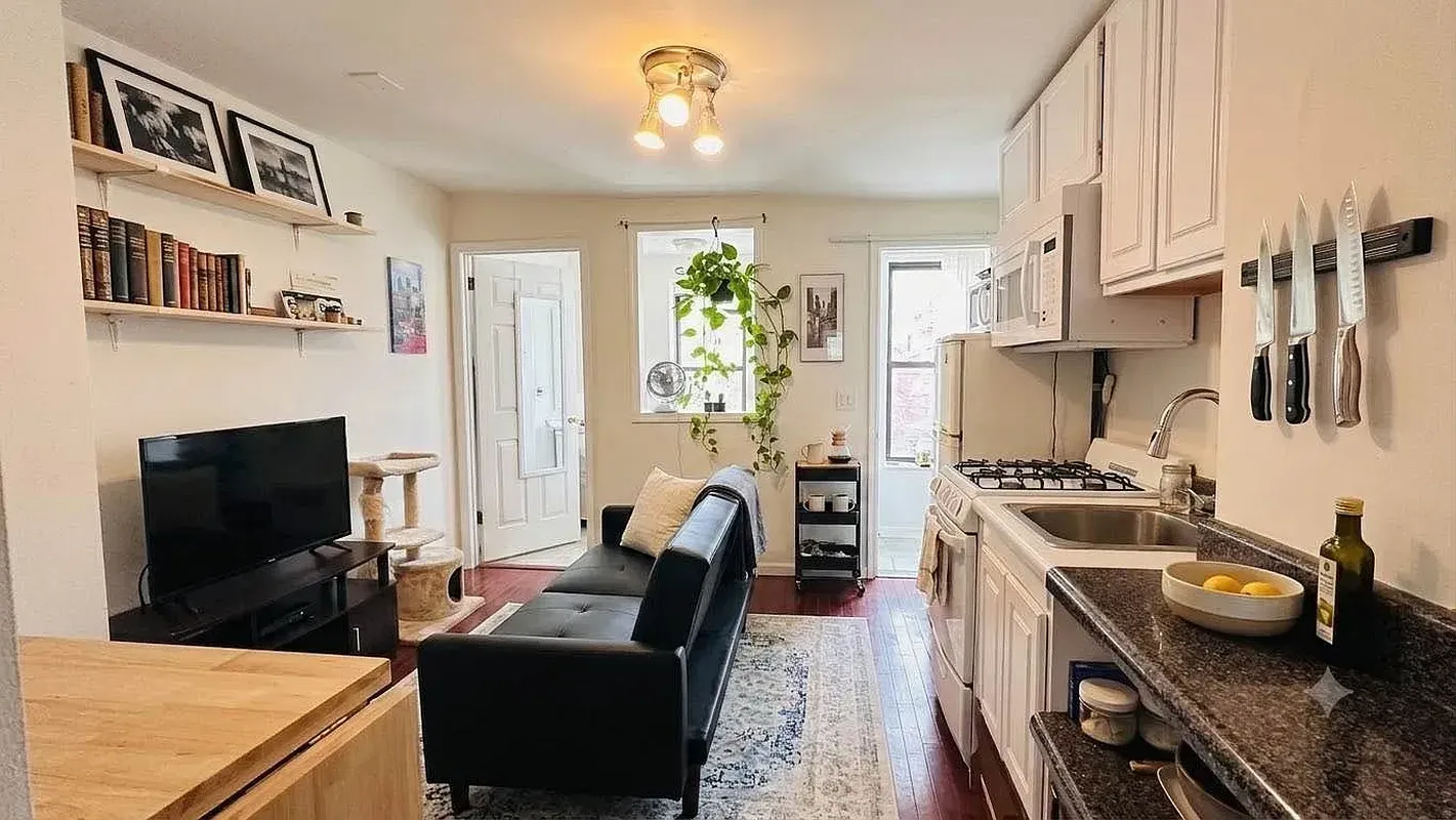 One bedroom at 518 East 6th Street, living room with black sofa and galley kitchen