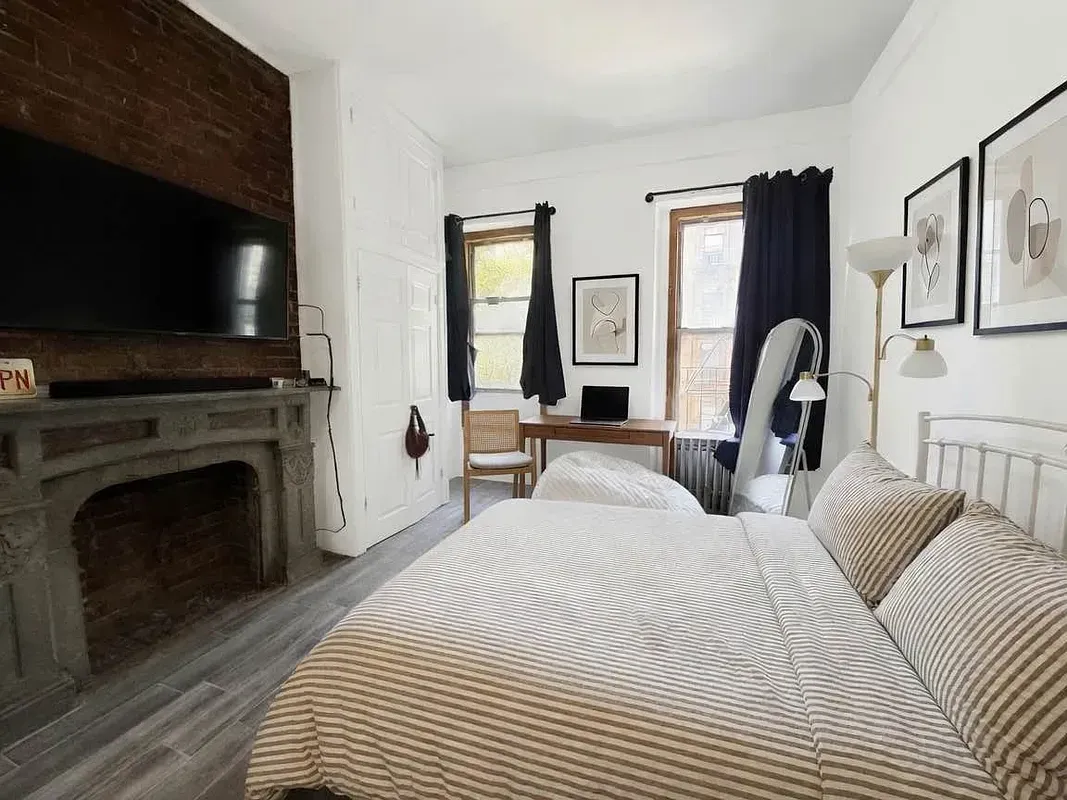 Two bedroom at 13 Saint Marks Place, bedroom with exposed brick and a fireplace