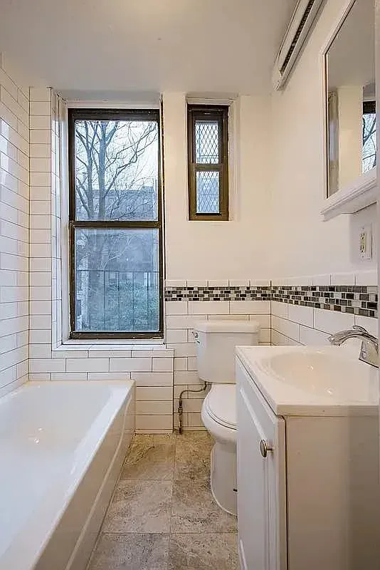Three bedroom at 520 East 6th Street, bathroom with tub, window and pedestal sink