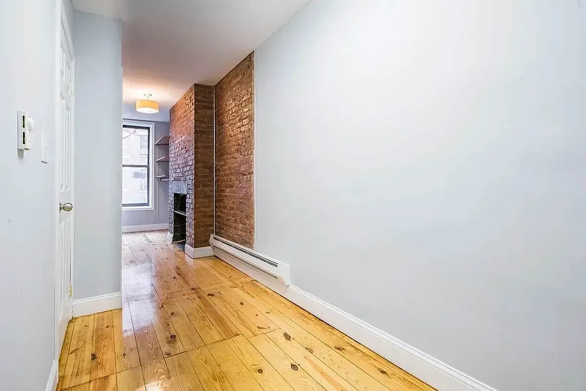 Three bedroom at 520 East 6th Street, hallway with exposed brick and window