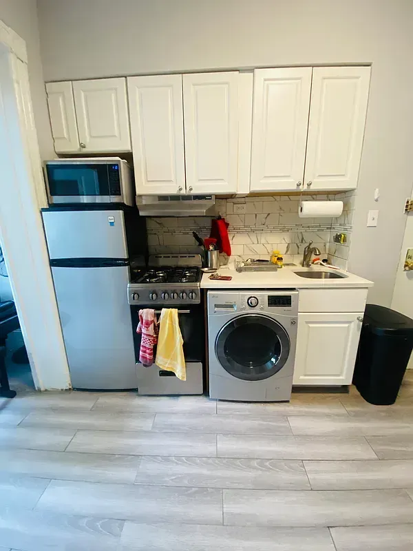 Three bedroom at 17 Saint Marks Place, kitchen with white cabinets and washing machine