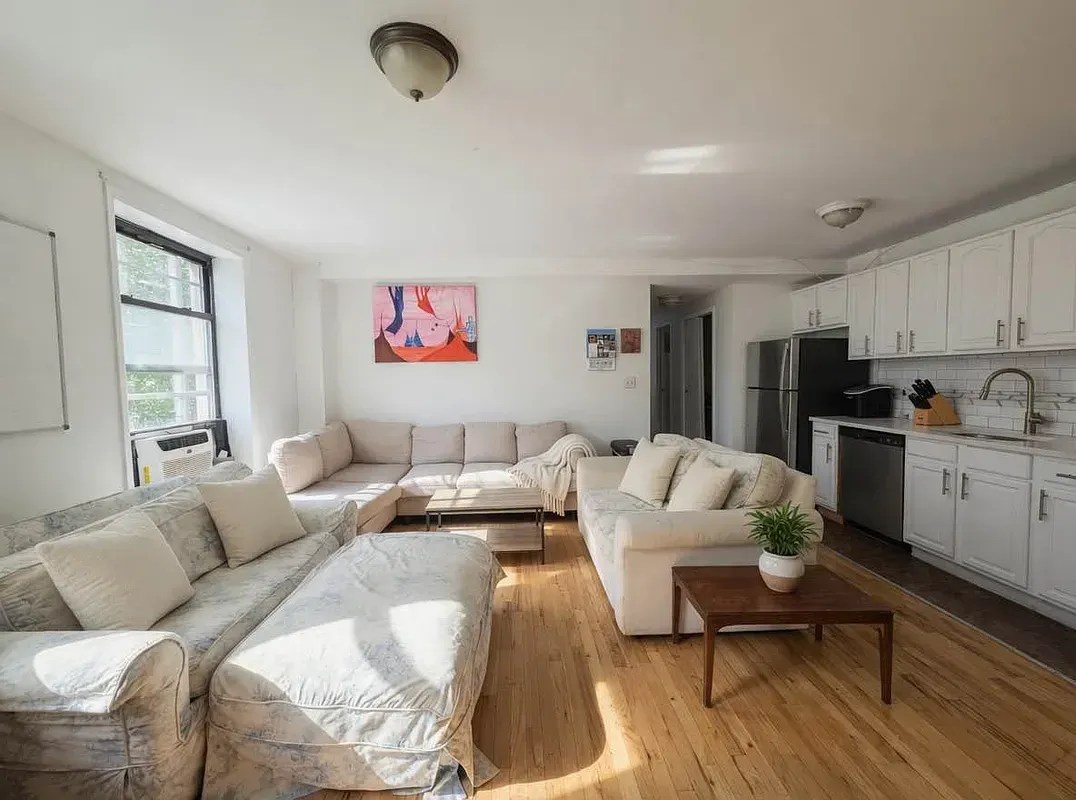 Four bedroom at 93 Avenue B, living room with white kitchen cabinets and windows