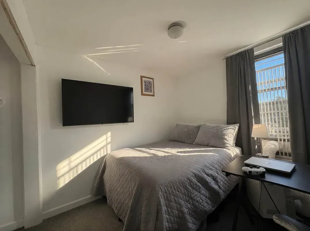Four bedroom at 93 Avenue B, bedroom with wall-mounted TV and window