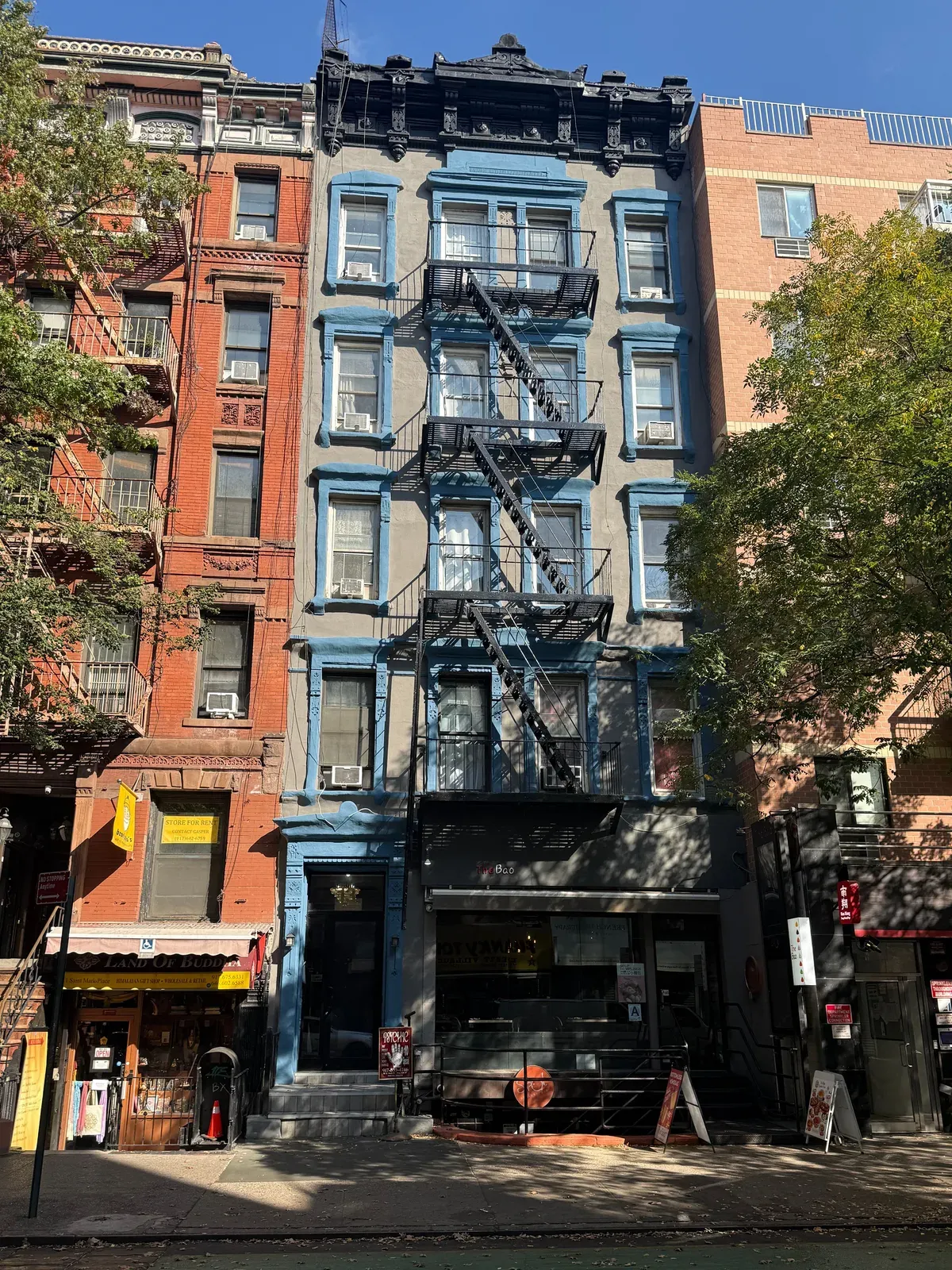 13 Saint Marks Place, a five-story walk-up with blue window trim, a fire escape and a restaurant at street level, seen from across the street