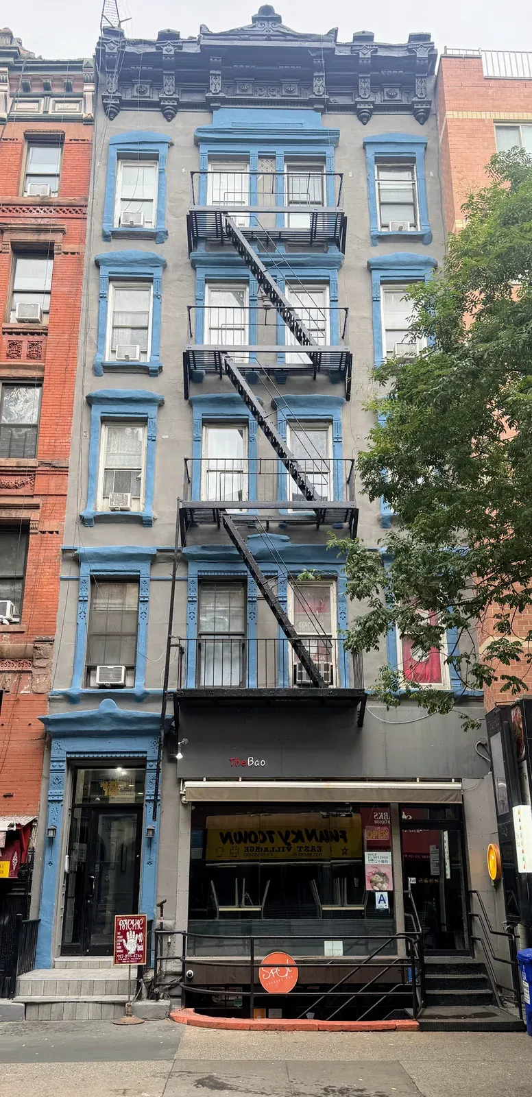 13 Saint Marks Place, a five-story walk-up with blue window trim, a fire escape and a restaurant at street level